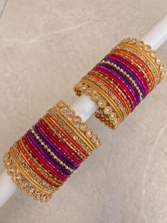 Large stack of Bright gold, purple, pink and orange bangle set with golden zircon kada bangles on the ends. Ready to Ship! Bangle Set Pink, Orange Bangles Set, Bangles Combination, Kada Bangles, Beautiful Bangles, Unique Mehndi, Bangle Box, Purple Sunset, Silk Thread Bangles