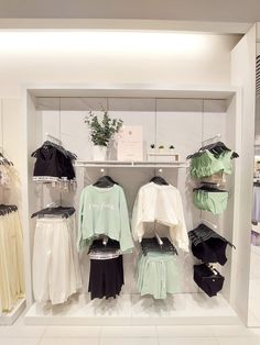 a clothing store with clothes on display in the front and behind it is a white wall