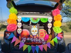 the trunk of a car is decorated with colorful paper decorations and sugar skulls, as well as tissue pom - poms