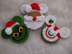 three crocheted santa claus ornaments on a white tablecloth with red, green and yellow trim