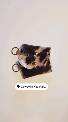 a pair of scissors sitting on top of a small animal print wallet with the word cow print keychain