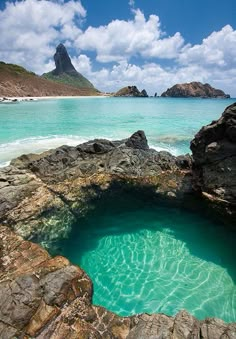 the water is crystal blue and clear with rocks in it's foreground, and an island in the distance