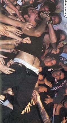 a large group of people standing around each other with their arms in the air and one person holding his head up