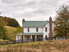 a large white house sitting on top of a lush green hillside