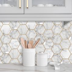 a kitchen counter with marble tiles and wooden utensils in front of the cabinets