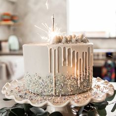 a white cake with icing and sprinkles on top sitting on a table