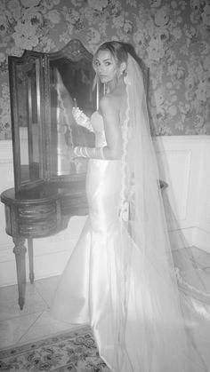 a woman in a wedding dress standing next to a mirror