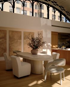 a dining room table with chairs and a vase filled with flowers on top of it