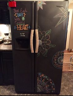 a black refrigerator with chalk drawings on the door and writing on the side that says start each day with grateful heart