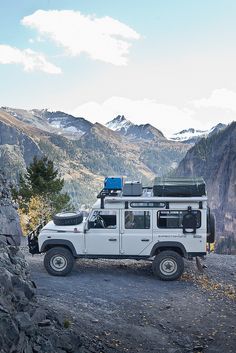 an off road vehicle parked on the side of a mountain with mountains in the background