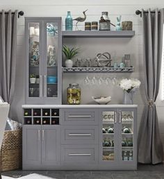 a grey cabinet with glass doors and shelves filled with wine glasses, vases and other items