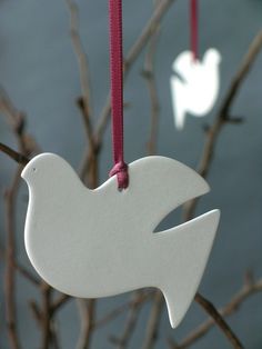 two white ornaments hanging from branches with water in the background