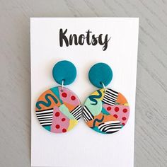 a pair of colorful earrings sitting on top of a white card with the words knotty written