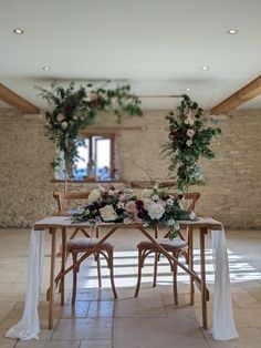 the table is set with flowers and greenery for an outdoor wedding reception at stone barn