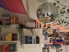 a disco ball hanging from the ceiling in a room with bookshelves and plants