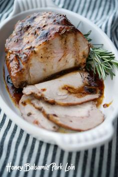 sliced pork in a white bowl with sauce and rosemary sprig on the side