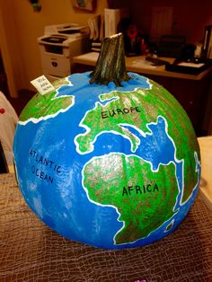 a large blue and green painted pumpkin sitting on top of a table