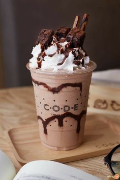 an ice cream sundae with chocolate and whipped cream on top, sitting on a wooden tray