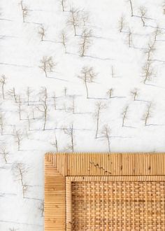 a bamboo bed frame against a white wall with grass growing on it's sides