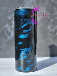 a blue and black glass vase sitting on top of a white table next to a gray wall