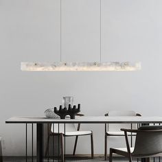 a dining room table and chairs with lights hanging from the ceiling