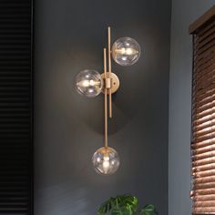 three lights that are on the wall next to a potted plant