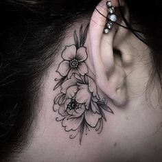 a woman's behind the ear tattoo with flowers