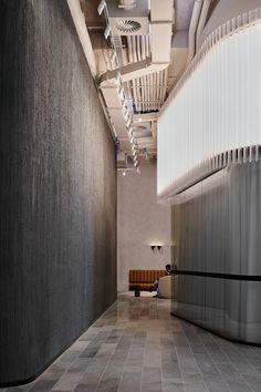 an empty hallway with gray and white tiles on the floor next to a bench in front of a wall