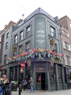 people are standing outside the building with flowers on it