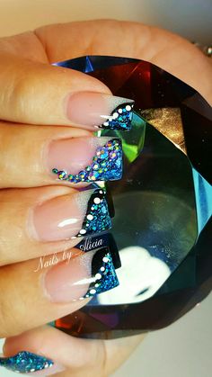 a woman's hand with blue and white nail designs on her nails, next to a diamond