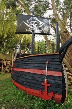 an old pirate ship with a flag and anchor on it's side sitting in the grass