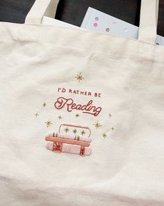 a tote bag that says i'd rather be reading next to some books