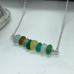 "Sterling silver necklace with genuine multi-coloured sea glass beads, including some rare colours.    The sea glass beads are approximately 7mm diameter, although they are random shapes as would be expected from sea glass. There are 8 beads and the total length is 4cm or 1.5\".  The necklace is 17.5\" / 19.5\" including the sea glass feature which allows you to adjust the length so the sea glass sits in the optimal position for you. Only 1 available.  Please note that some of the gemstones I use are natural stones; therefore exact sizes, shapes and colors vary, they may also have natural inclusions, which is part of the beauty of the gemstone. I aim to capture the true color of my gemstones, however they may look different on different screens All my silver items weighing over 7.78g are h Rare Colours, Random Shapes, Sea Glass Beads, Silver Items, Silver Bar Necklace, Silver Bar, Sea Glass Necklace, Silver Bars, Glass Necklace