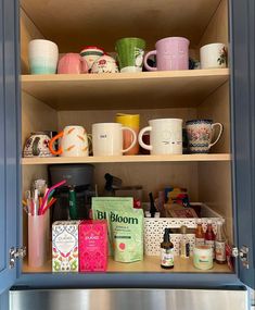 an open cupboard filled with coffee mugs and other items