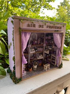 a doll house is set up in the shape of a bookcase with purple curtains