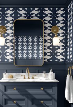 a bathroom with blue and white wallpaper, gold fixtures and a large mirror over the sink