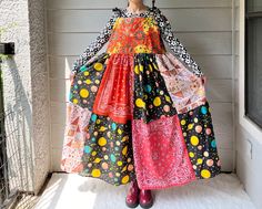 a woman wearing a colorful dress standing in front of a house with her hands on her hips