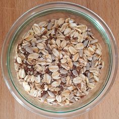 a glass bowl filled with oats on top of a wooden table