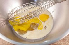 the whisk is being mixed with ingredients in a silver bowl on top of a wooden table