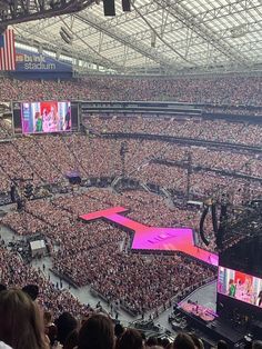 a large stadium filled with lots of people and one stage is lit up for a concert