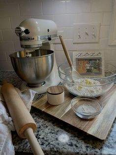 a kitchen counter topped with a mixer, bowl and wooden spatula next to other ingredients