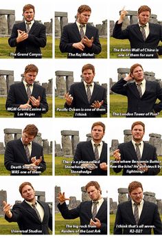 a man in a suit and tie making gestures with his hands while standing next to a stonehenge