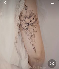 a woman's arm with a flower and arrow tattoo on the left side of her arm