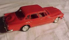 a red toy car sitting on top of a white sheet