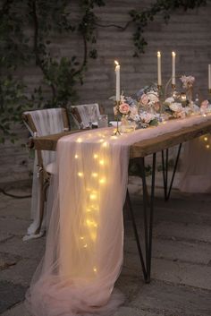 a long table with candles and flowers on it is set up for an outdoor dinner