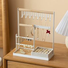 a white jewelry box sitting on top of a wooden table next to a lamp and vase