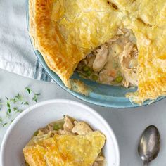 a chicken pot pie in a blue dish with a serving spoon next to the pie