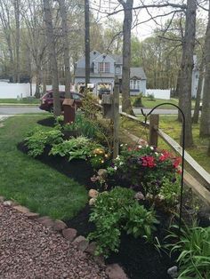 a garden with lots of plants and flowers in the front yard, next to a house