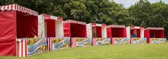 a row of red and white striped booths sitting on top of a lush green field