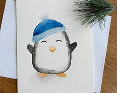 a watercolor painting of a penguin wearing a blue hat